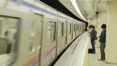 Commuters-waiting-in-a-Tokyo-subway-station-with-a-train-coming-in-the-station