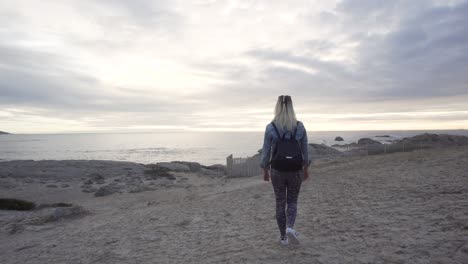 Girl-walking-at-Maidens-Cove-with-a-view-to-Camps-Bay-and-Table-Mountain-during-Sunset-in-Cape-Town,-South-Africa-in-Slow-Motion