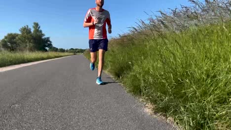 Primer-Plano-De-Las-Piernas-Siguiendo-Un-Sendero-Masculino-Runner-En-El-Dique-Del-Valle-De-Las-Llanuras-Aluviales