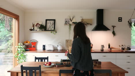 Mujer-Joven-Encendiendo-Velas-En-Una-Cocina-De-Estilo-Y-Alojamiento-Para-Estancias-Cortas.