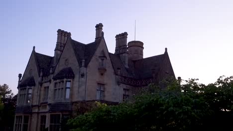 Toma-Aérea-De-La-Mansión-Junto-Al-Lago-Cheltenham-Gloucestershire-Casa-Verical-Revelada-En-Una-Hermosa-Luz-Dorada-Del-Atardecer