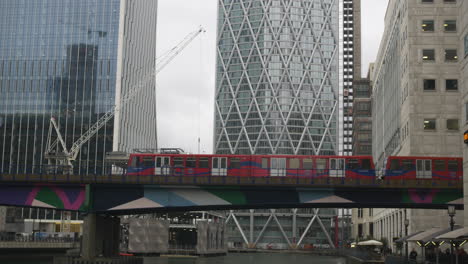 Ein-Zug-Fährt-über-Eine-Eisenbahnbrücke-In-Canary-Wharf-In-Den-DLR-Bahnhof