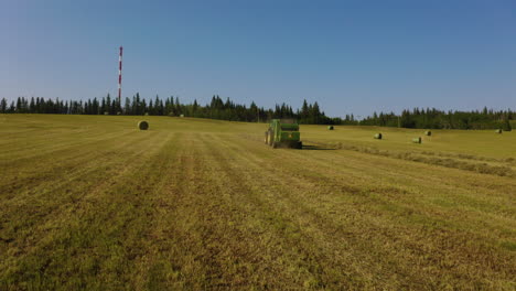 Aerial-view-flying-toward-a-tractor-baling-hay