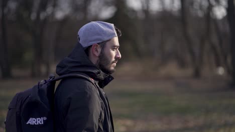 Stylish-young-caucasian-man-with-cap-walking-in-slow-motion-through-a-forest-at-day-time