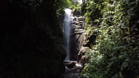 Tourists-trekking-through-rocks-while-Tall-Waterfall-reveals-on-background