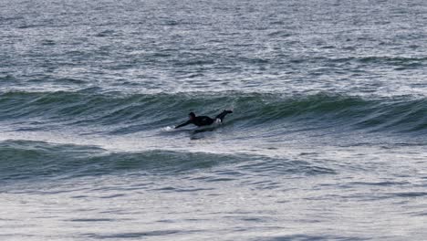 Man-Effortlessly-Riding-A-Surfboard-On-The-Waves,-Balanced-And-Focused