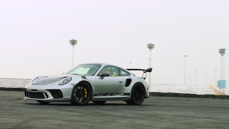 Toma-En-Cámara-Lenta-De-Un-Porsche-GT3-RS-Plateado-En-Una-Pista-De-Derrape