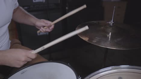 Young-man-playing-drum-set-in-basement-during-practice-session