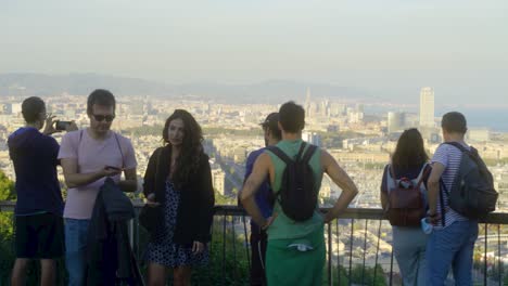 People-on-viewpoint-overlooking-city-and-harbor-and-taking-photos-with-smartphone-during-sunset