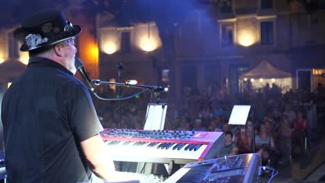 Hat-wearing-singer-playing-piano-on-stage-and-clapping-hands-to-hype-up-the-audience