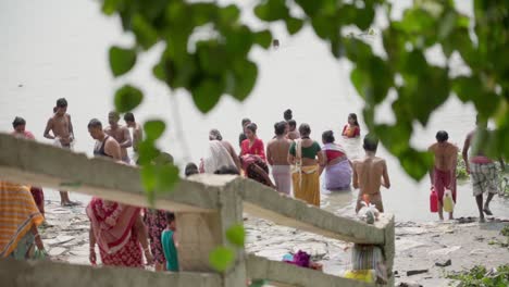 Gente-Bañándose-Y-Nadando-En-La-Orilla-Del-Río-Ganga,-Rani-Rashmoni-Ghat,-Disparado-A-Través-De-Hojas-De-árbol,-Cámara-Lenta