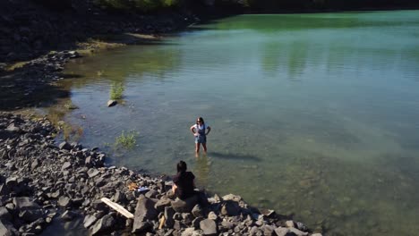 two-woman-standing-on-the-edge-of-a-lake-next-to-the-trans-canada-sea-to-sky-highway-near-Whistler-BC