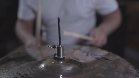 Young-man-playing-drums-in-basement,-parallax-around-hi-hat-cymbal,-close-up