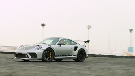 Coche-Deportivo-Gris-Pasando-Por-Una-Pista-En-Cámara-Lenta-Con-Una-Ligera-Oscilación-De-La-Cámara