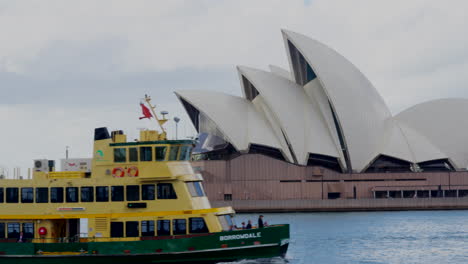 A-large-green-and-yellow-ferry-passes-by-the-Sydney-opera-house-in-Australia