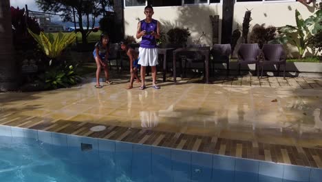 A-rearward-aerial-shot-of-two-kids-jumping-into-the-pool