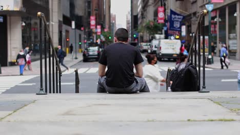 Man-sitting-on-the-steps-looking-at-people-walking-by-while-smoking