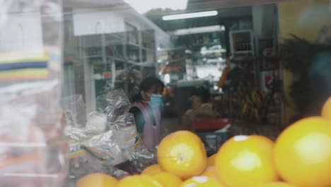 A-woman-wearing-a-mask-is-selling-food-in-her-store