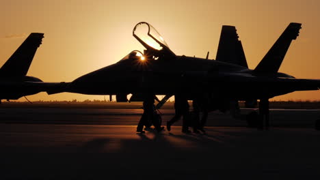 Silueta-De-Oficiales-Navales-Caminando-Frente-A-Un-ángel-Azul-En-La-Pista-Mientras-Los-Aviones-Se-Preparan-Para-Una-Rutina-De-Exhibición-Aérea-Al-Amanecer-Temprano-En-Key-West