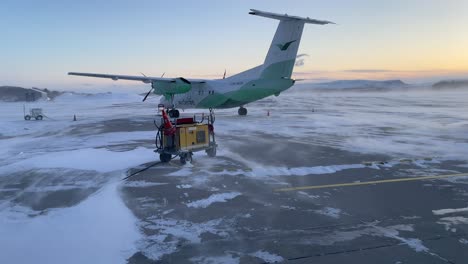 Toma-En-Cámara-Lenta-De-Un-Avión-De-Hélice-Nacional-Dash-8-300-Listo-Para-Embarcar-Al-Pasajero-Para-Despegar-Durante-Fuertes-Vientos-En-El-Aeropuerto-De-Bodo