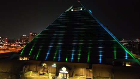 Memphis-Pyramid,-Der-Bass-Pro-Shop-In-Memphis,-Tennessee-Bei-Nacht-Mit-Drohnenvideo,-Das-Sich-Vom-Boden-Erhebt