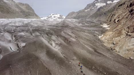 Toma-Aérea-De-Dos-Equipos-De-Cuerdas-Descendiendo-Por-Un-Glaciar-Con-Una-Montaña-Al-Fondo