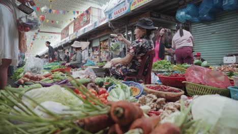 Vendedor-Local-Y-Puesto-Tradicional-Que-Vende-Frutas-Y-Verduras-Frescas,-Textiles-Y-Ropa-En-El-Famoso,-Concurrido-Y-Colorido-Mercado-De-Estafas-En-Danang,-Vietnam-En-Asia