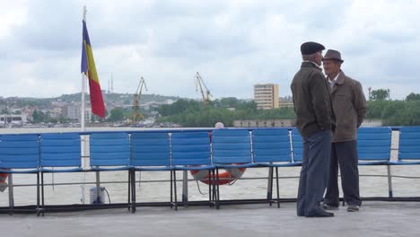 Dos-Viejos-Rumanos-Hablando-En-La-Cubierta-De-Un-Ferry-De-Pasajeros-Del-Danubio-En-Movimiento