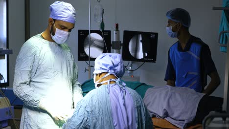 Assistant-handing-surgery-tools-to-practitioner-dark-operating-theater-closeup