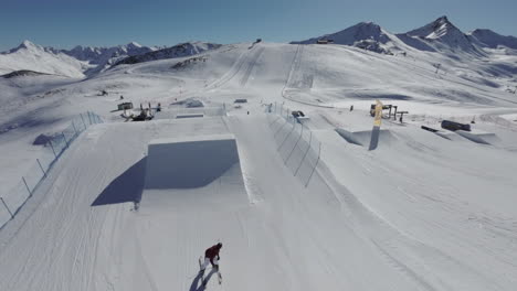 Toma-De-Drone-De-Un-Esquiador-De-Estilo-Libre-Haciendo-Giros-Y-Volteretas-Después-Del-Lanzamiento-Desde-Una-Rampa-En-Un-Parque-De-Nieve