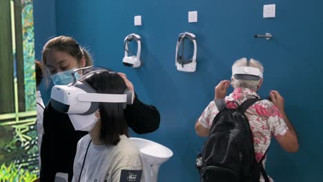 Besucher-Versuchen,-Virtual-Reality-Headsets-Zu-Tragen,-Um-Einen-Immersiven-Abenteuersimulator-Zu-Erleben