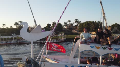 Cámara-Lenta-De-Turistas-Sentados-En-El-Techo-De-Un-Barco-Turístico-En-Faluca-Local-En-Egipto-En-El-Río-Nilo-Rumbo-A-La-Isla-Banana-En-Luxor,-Egipto