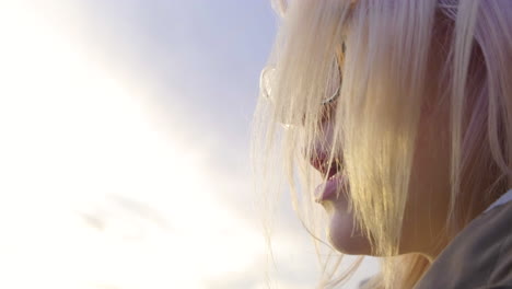 Young-woman-with-glasses-sitting-outside-during-Golden-Hour---Close-Up---4K