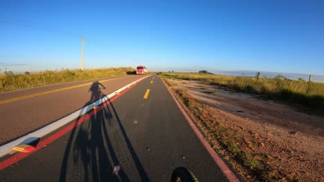 Cyclist-cycling-along-the-marked-bicycle-safety-lane-on-a-road-with-truck-traffic,-POV-video