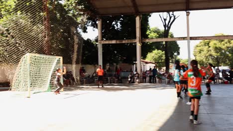 Young-school-girls-handball-match,-while-a-girl-throws-the-ball-in-the-goal