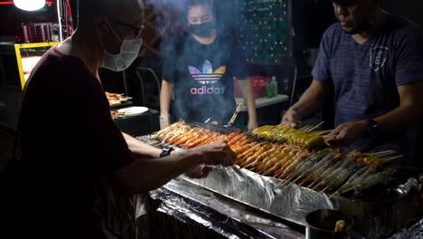 Satay-Verkäufer-Sind-Fleißig-Damit-Beschäftigt,-Garnelen-Satay-Im-Lau-Pa-Sat-Aufzuspießen