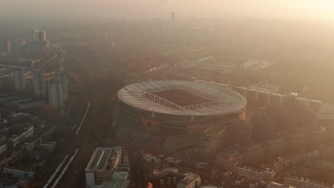 Tiro-Aéreo-Adelantado-Con-Plataforma-Rodante-Hacia-El-Estadio-De-Fútbol-Arsenal-Retroiluminado-Por-El-Sol