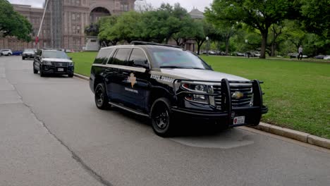 Edificio-Del-Capitolio-Del-Estado-De-Texas-En-Austin,-Texas-Con-Video-De-Cardán-Caminando-Por-La-Carretera-Con-Autos-De-Policía-Estatal