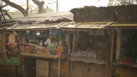 Poor-and-old-Shopkeeper-looking-outside-in-rainy-day,-monsoon-season,-slow-motion-shot-of-rain-drops