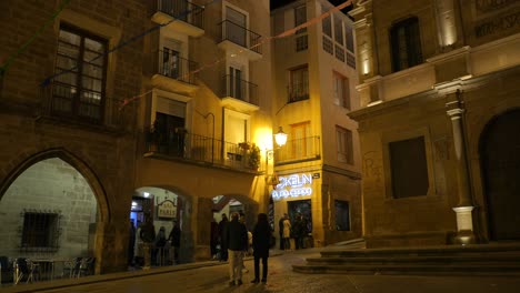 Gente-Visitando-Y-Disfrutando-De-La-Noche-En-El-Bar-De-La-Plaza-Principal-De-La-Ciudad-Histórica-De-Alcañiz,-España.