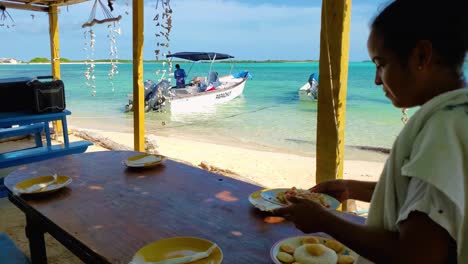 Mujer-Latina-Sirve-Arepas-Venezolanas-Producto-Típico-De-Comida,-Restaurante-De-Playa,-Los-Roques