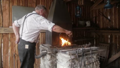 Un-Recreador-De-Herrero-Da-Vida-A-La-Historia-Al-Retratar-A-Un-Herrero-Tradicional,-Mostrando-El-Arte-Y-El-Comercio-Del-Trabajo-Del-Metal-Con-Herramientas-Y-Métodos-Auténticos.