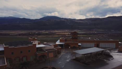 beautiful-winery-resort-on-the-edge-of-a-hill-overlooking-large-vineyard-approaching-aerial-4k-stabilized