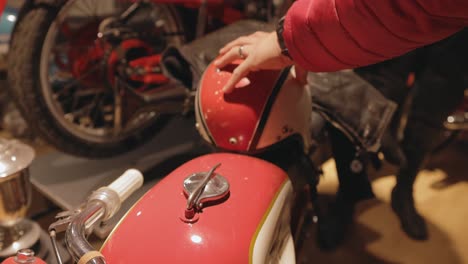 Un-Joven-Mirando-Y-Tocando-Un-Casco-Antiguo-Y-Una-Motocicleta-Dentro-Del-Museo-Del-Motor-De-Motala-En-Suecia