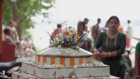 Out-of-focus-people-passing-by-a-holy-place-for-hindus-with-incense-sticks-in-it,-slow-motion