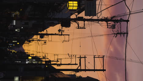 Vertical-shot-of-a-vibrant-sunset-over-a-tram-line-within-downtown-Kyoto