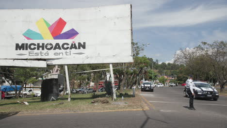 A-policewoman-directing-traffic-on-a-highway-outside-of-Uruapan-in-Michoacán,-Mexico