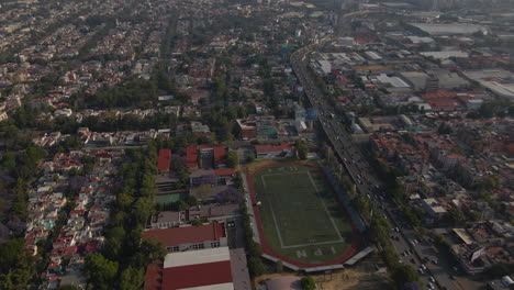 Luftschwenkansicht-Mexiko-Stadtbild-Gebäudepanorama-Mit-Fahrzeugen-Im-Starken-Stadtverkehr-Und-Stadion-Im-Sommer