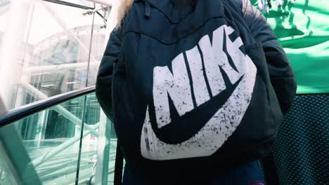 Young-woman-wearing-black-Nike-backpack-on-the-escalator