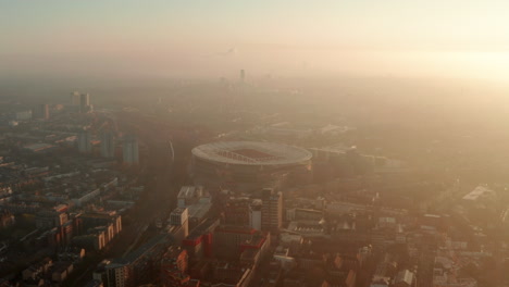 Toma-Aérea-Con-Plataforma-Rodante-Hacia-El-Estadio-De-Fútbol-Arsenal-Retroiluminado-Por-El-Sol.